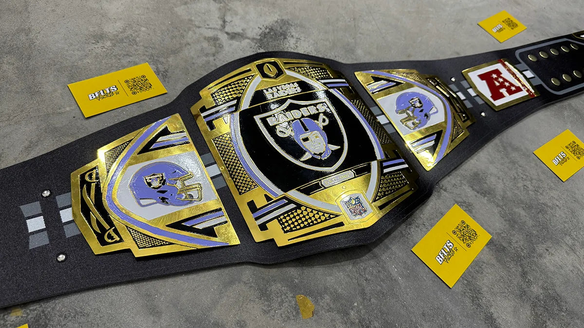 Las Vegas Raiders championship belt diagonal angle view, gold brass plates and printed black leather strap NFL fan collectible