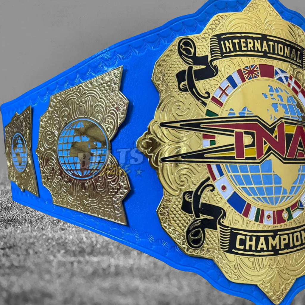 TNA International Championship Belt side plates angled close-up showing gold-plated brass TNA side plates on blue leather strap