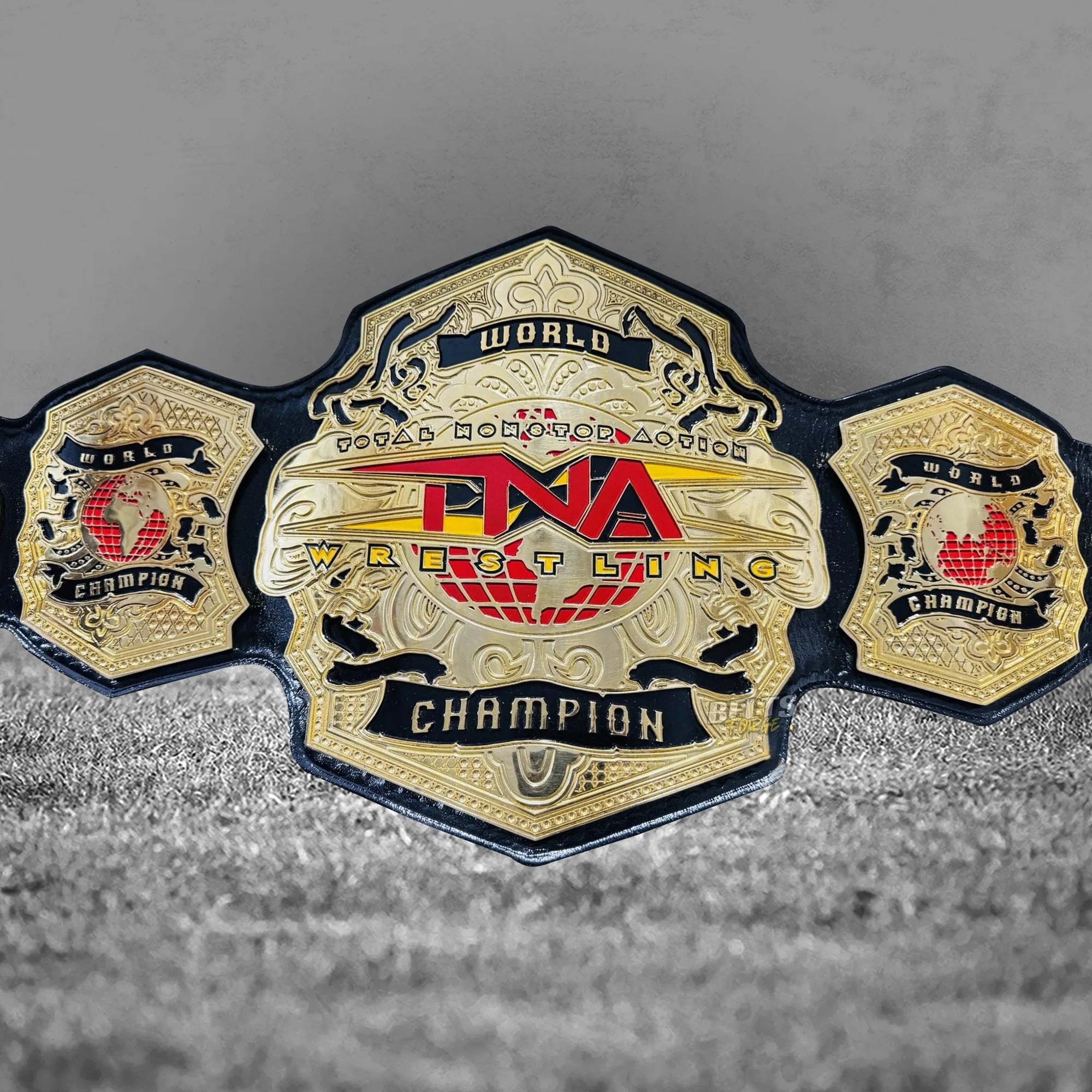 TNA World Heavyweight Championship Belt center plate alternate detail showing CNC-engraved gold-plated brass TNA globe design