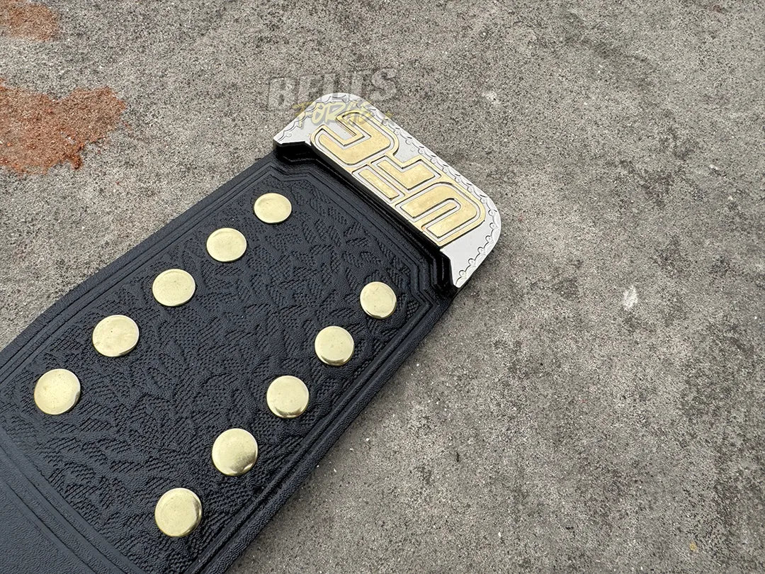 UFC Classic Championship Belt strap end tip close-up showing gold dome studs and floral embossed leather texture