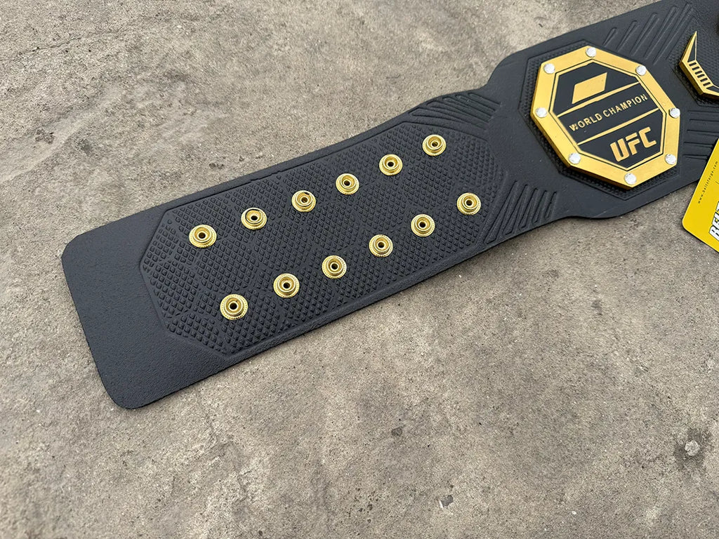 UFC Legacy Championship Belt leather strap close-up showing gold rivet studs and carbon-texture emboss detail