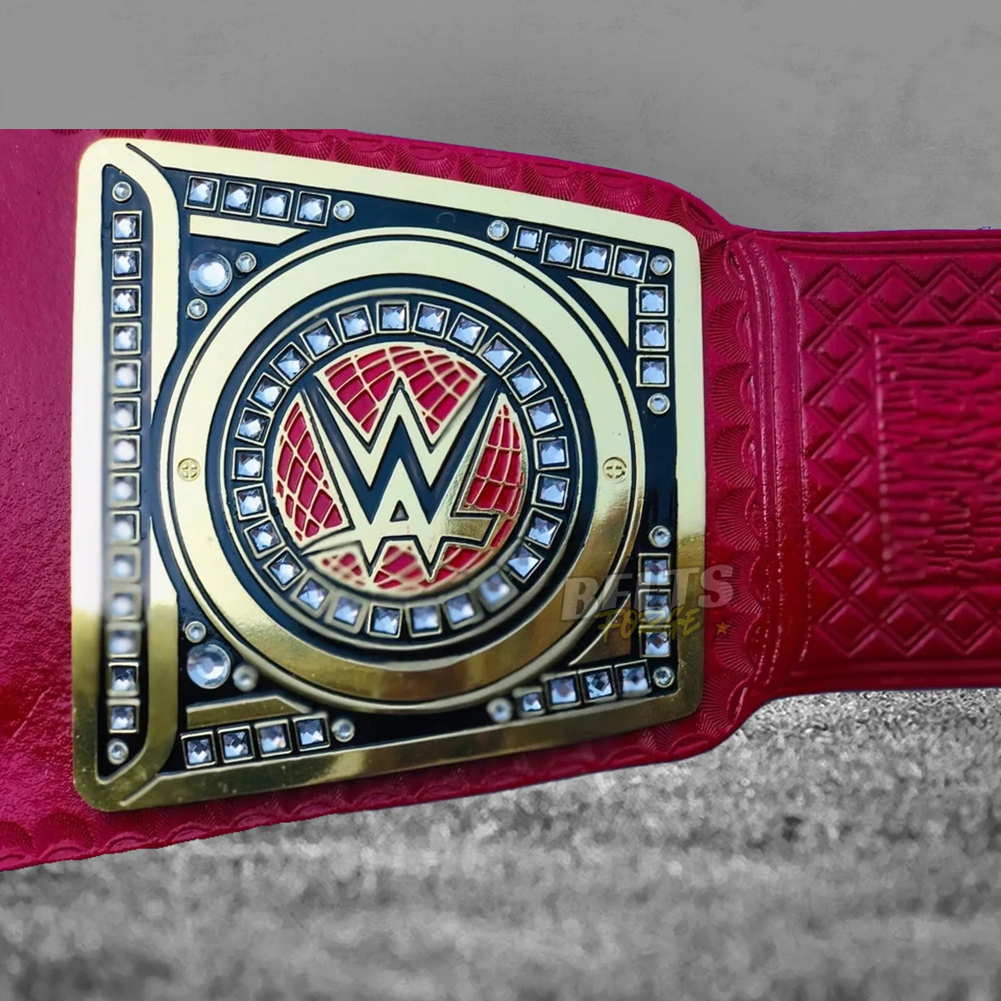 Pink Universal Championship Belt side plate detail showing gold-plated brass side plate on genuine pink leather strap