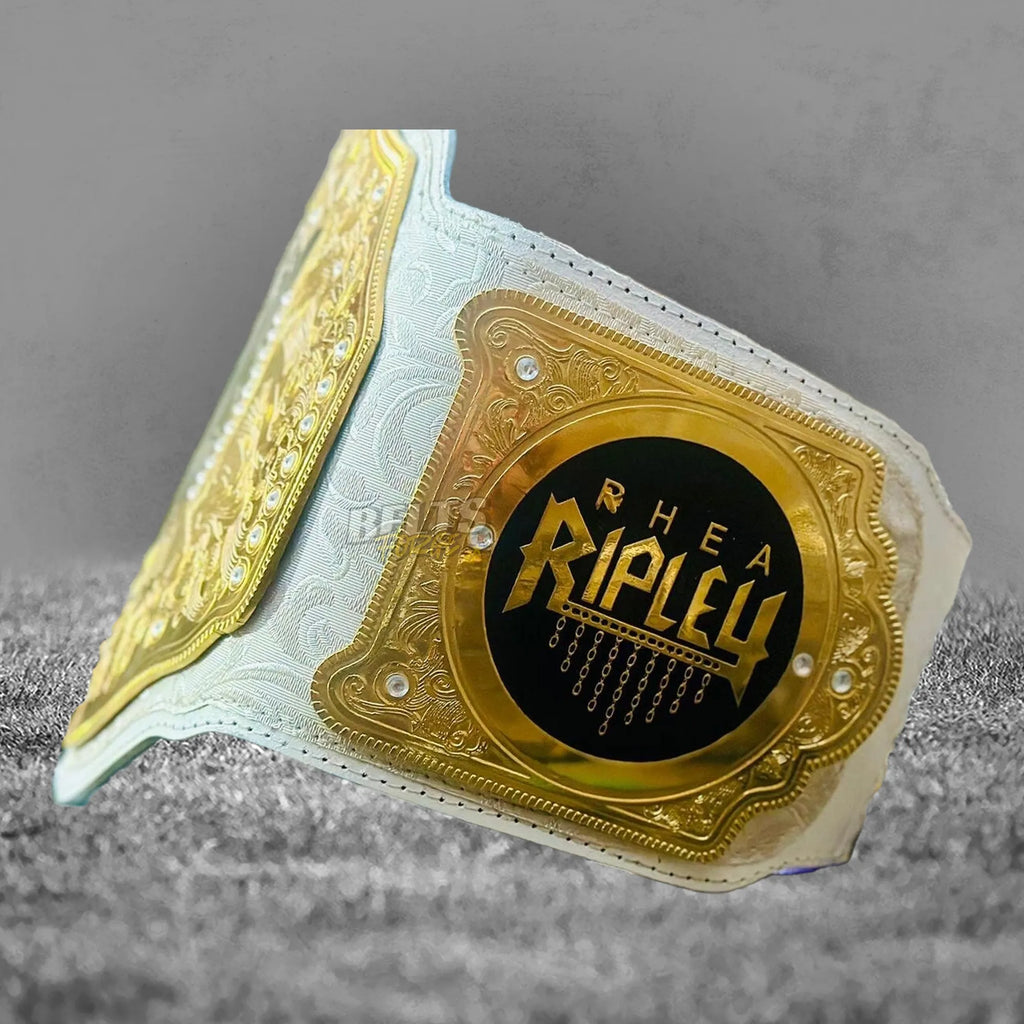 Rhea Ripley championship belt plate angled close-up showing gold brass engraving and Women's World Championship detail
