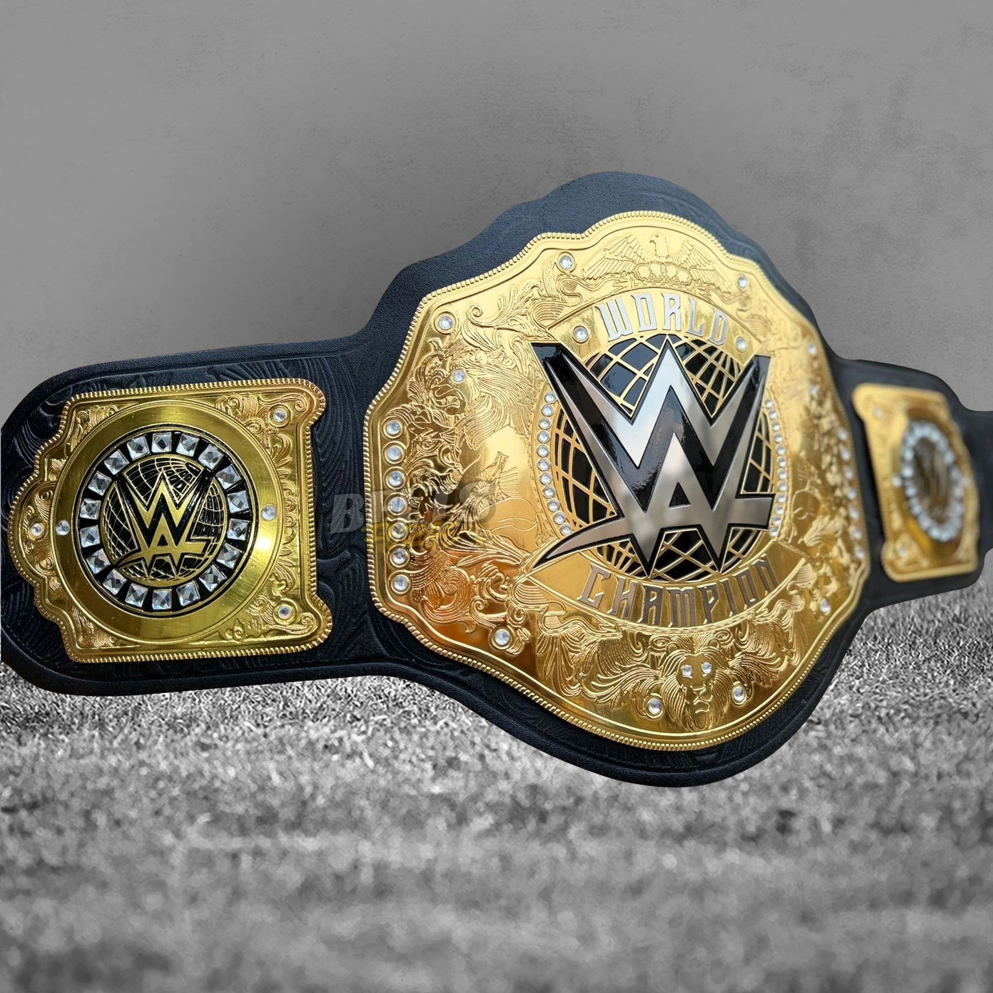 WWE World Heavyweight Championship Belt replica angled left view showing gold WWE logo plate, rhinestone crystal border and left square side plate with globe logo