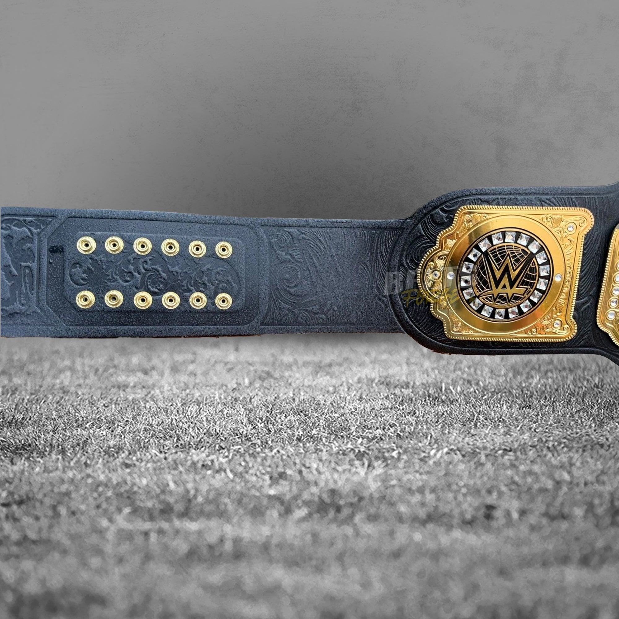 WWE World Heavyweight Championship Belt back strap detail showing deep floral embossed genuine black leather, gold studs and square side plate close-up