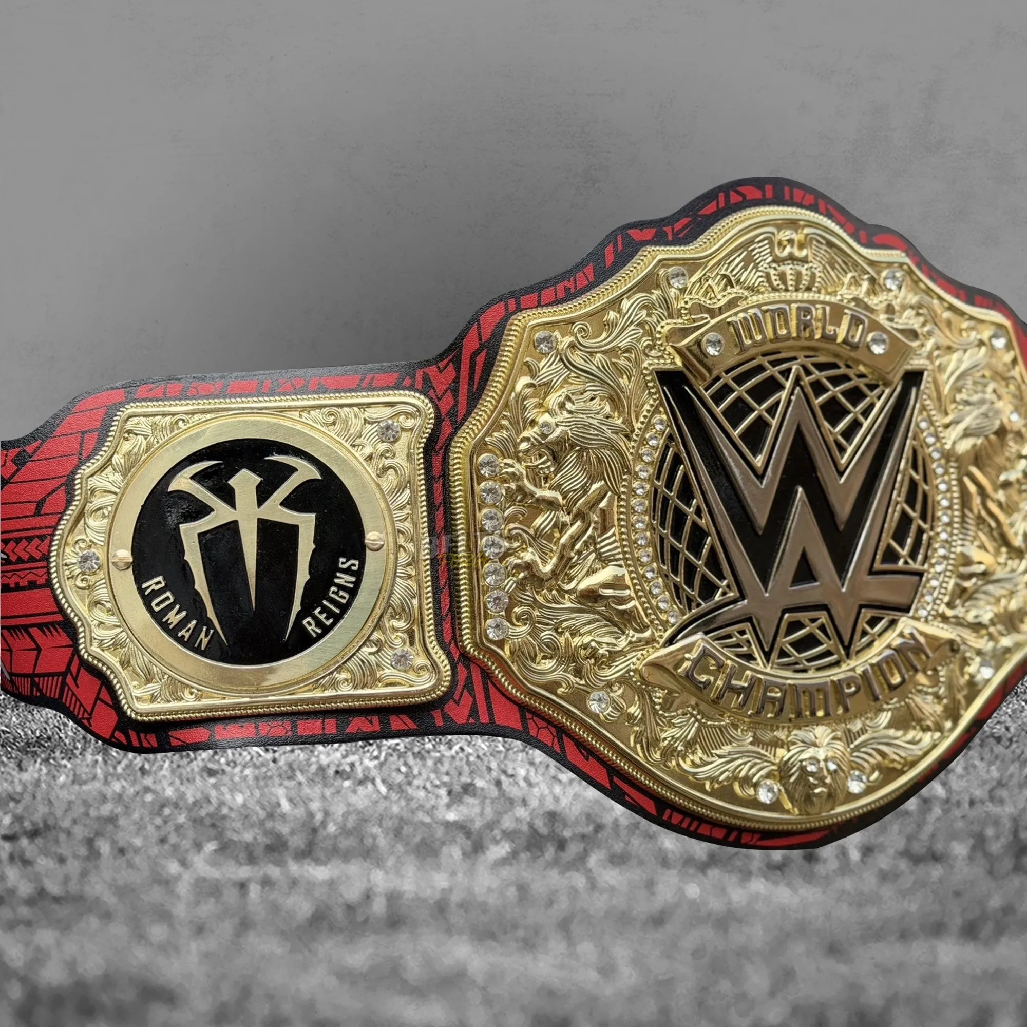 Roman Reigns championship belt full front display view, gold-plated brass tribal main plate and OTC side plates on printed leather strap