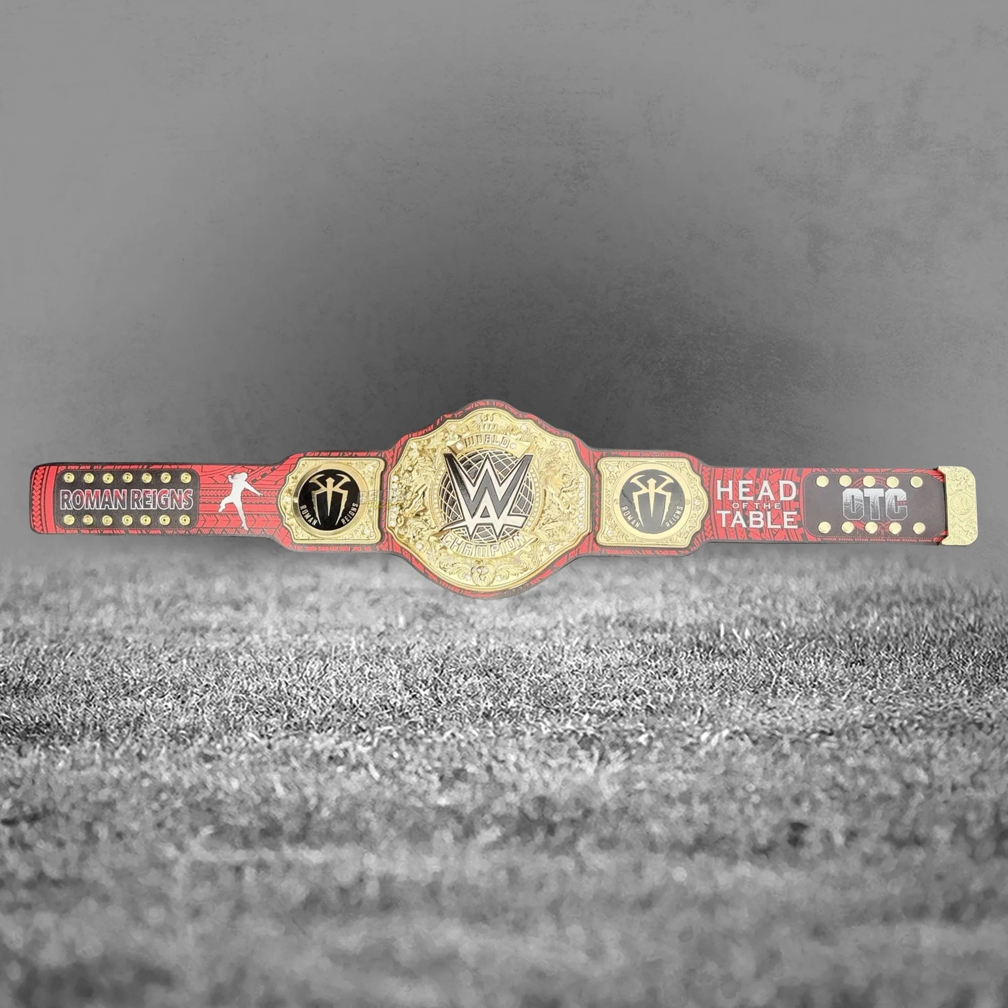 Roman Reigns Head of the Table OTC side plate detail, gold-plated brass tribal design on printed leather strap close-up
