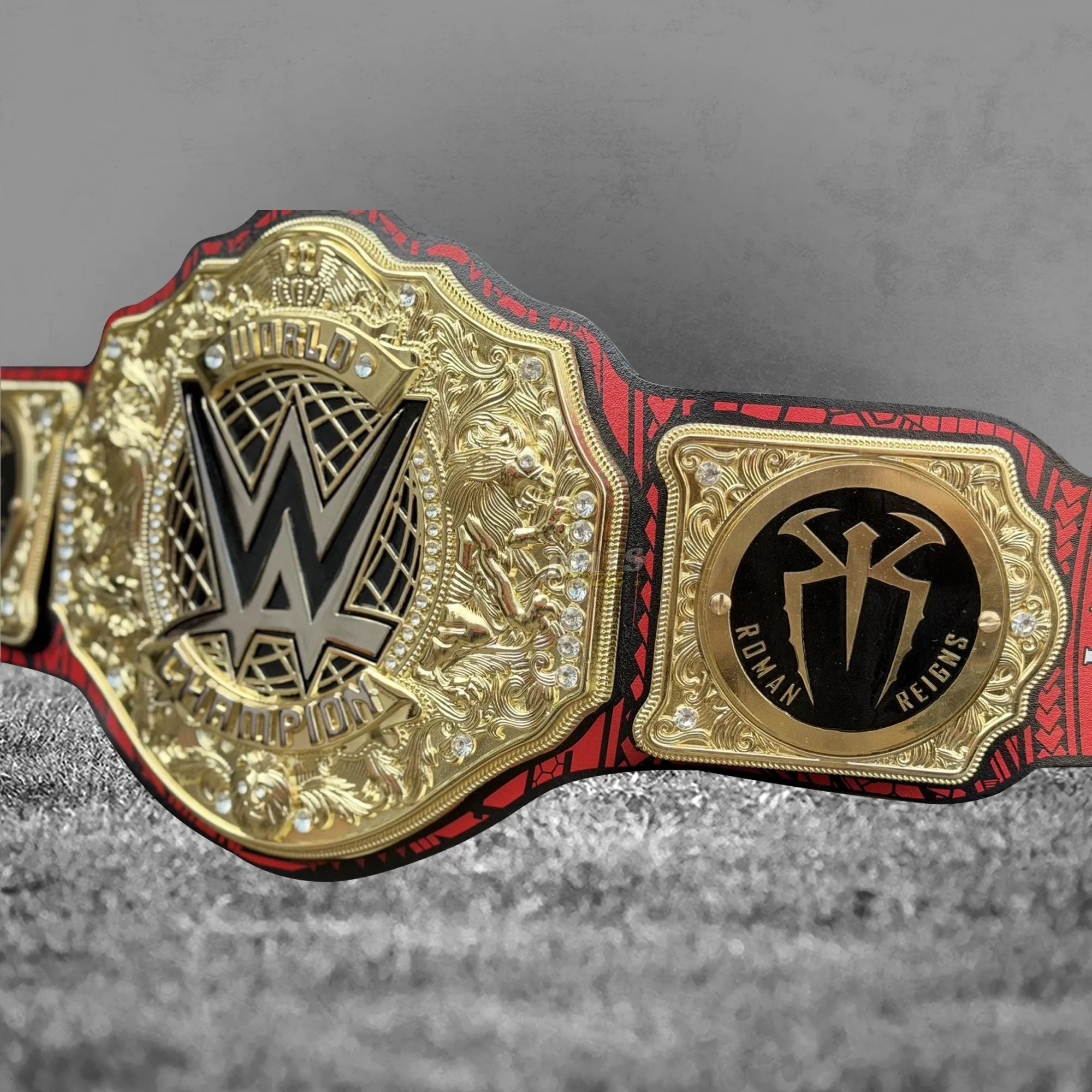 Roman Reigns OTC championship belt strap tip detail showing tribal print leather and gold-plated end hardware