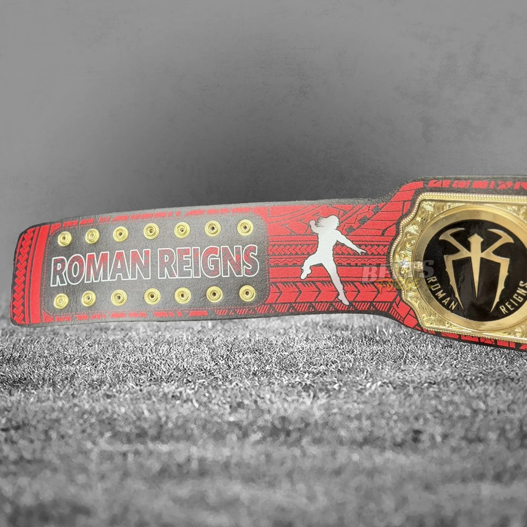 Roman Reigns Head of the Table championship belt side strap view showing full tribal printed leather strap and gold OTC plate