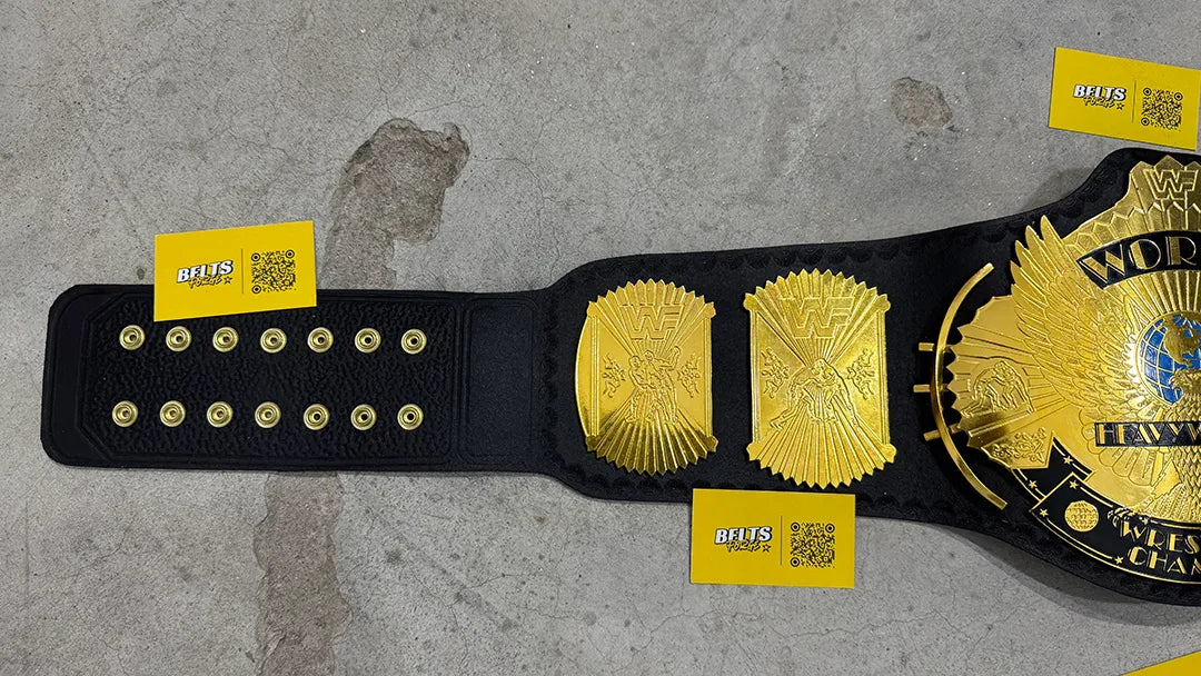 WWF Winged Eagle Championship Belt left strap close-up showing brass side plates, gold dome studs and genuine leather texture
