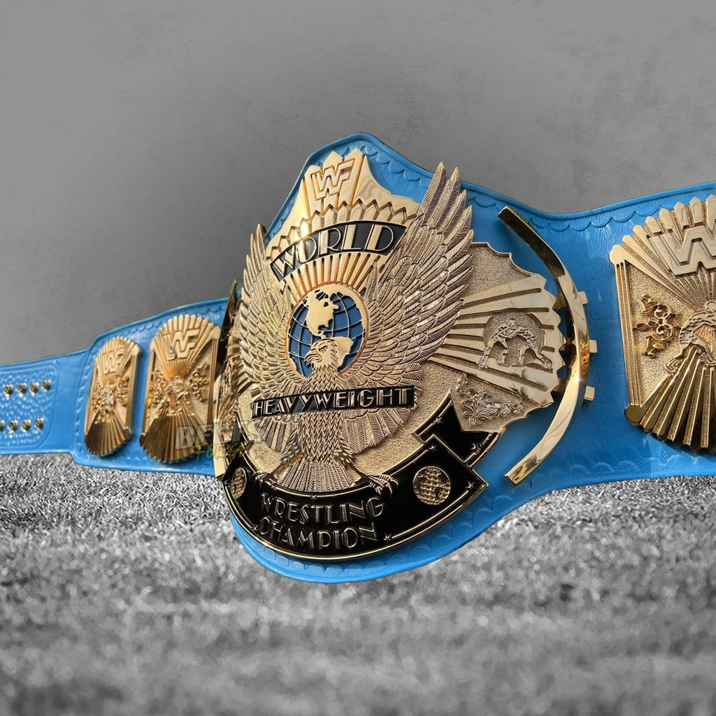 Winged Eagle Championship Belt angled center plate close-up showing gold eagle and globe engraving detail on blue leather strap