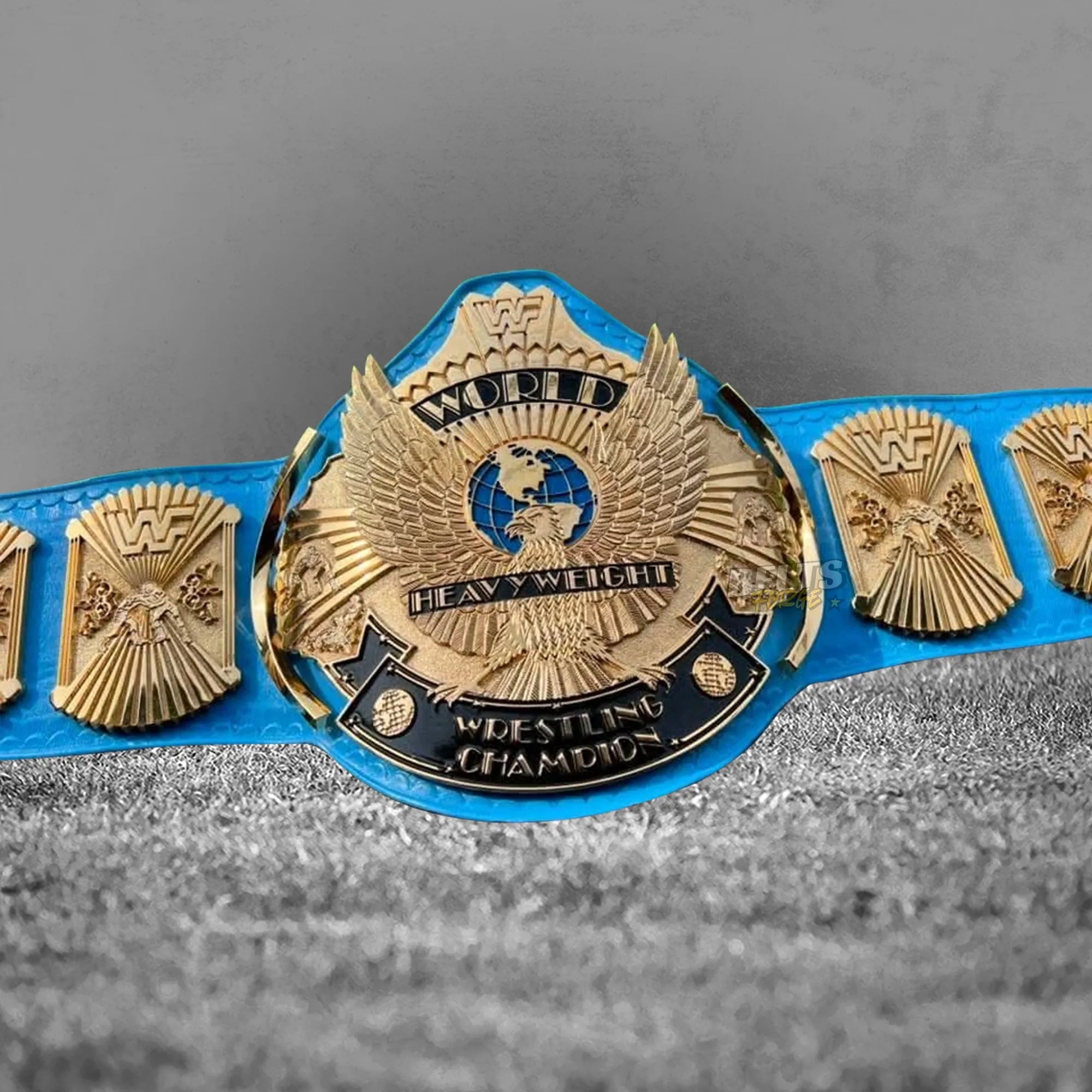 Winged Eagle Championship Belt center plate close-up showing CNC-engraved gold-plated brass eagle design on blue leather